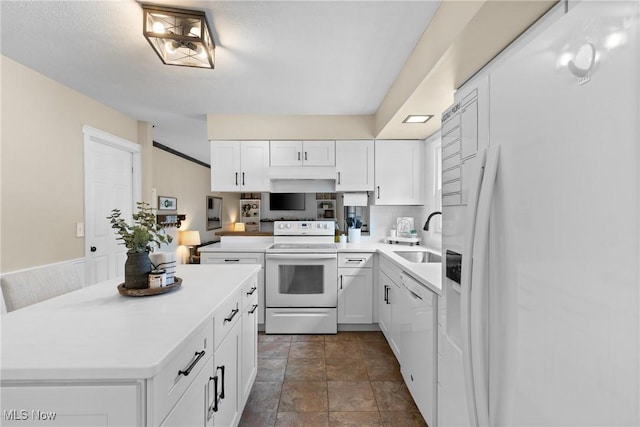 kitchen with white appliances, white cabinets, a sink, and light countertops