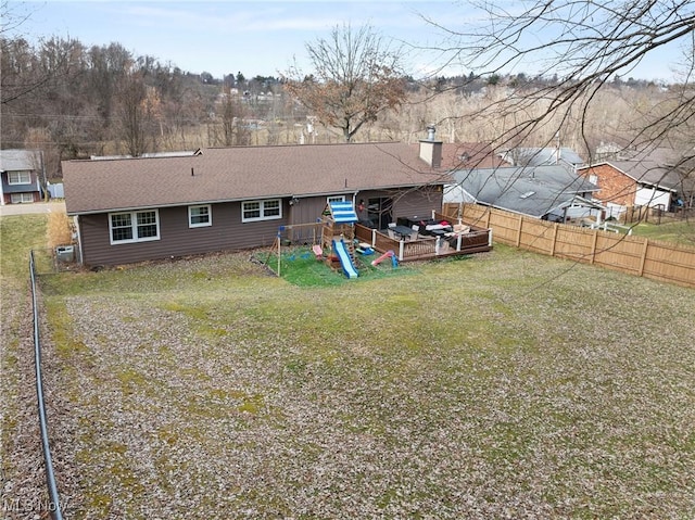 rear view of house with a yard, roof with shingles, fence, and a chimney