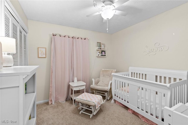 bedroom with a nursery area, a closet, carpet flooring, and a ceiling fan