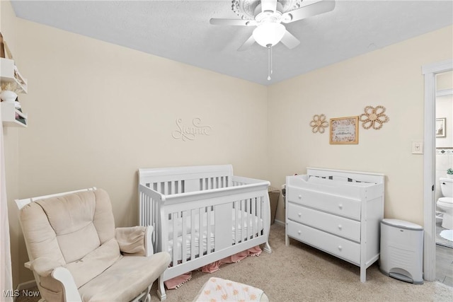 bedroom featuring carpet floors, a nursery area, and ceiling fan