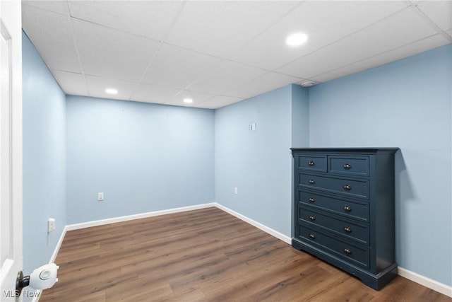 finished below grade area featuring recessed lighting, a drop ceiling, dark wood finished floors, and baseboards