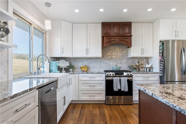 kitchen with dark wood finished floors, tasteful backsplash, appliances with stainless steel finishes, white cabinets, and a sink