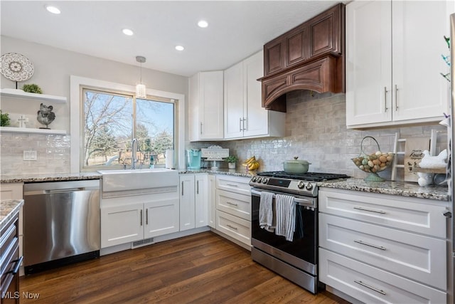 kitchen with white cabinets, dark wood-style flooring, light stone countertops, stainless steel appliances, and a sink