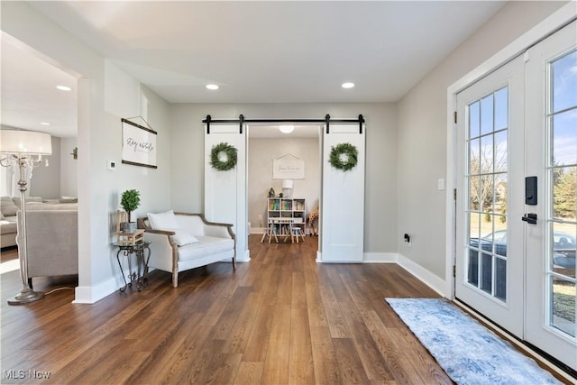 interior space with a barn door, baseboards, wood finished floors, and recessed lighting