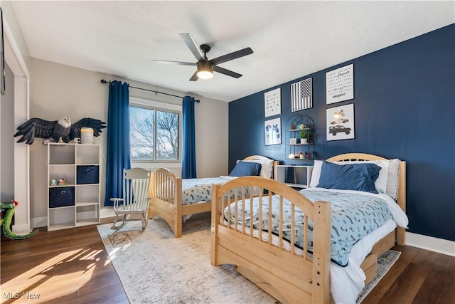 bedroom with ceiling fan, baseboards, and wood finished floors