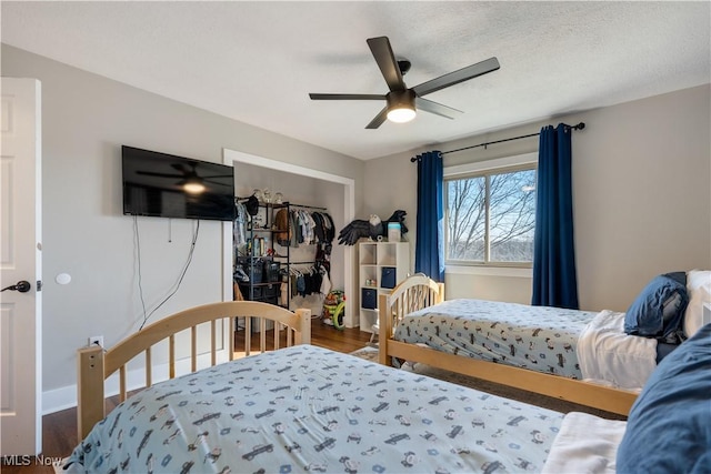 bedroom with baseboards, a textured ceiling, a ceiling fan, and wood finished floors