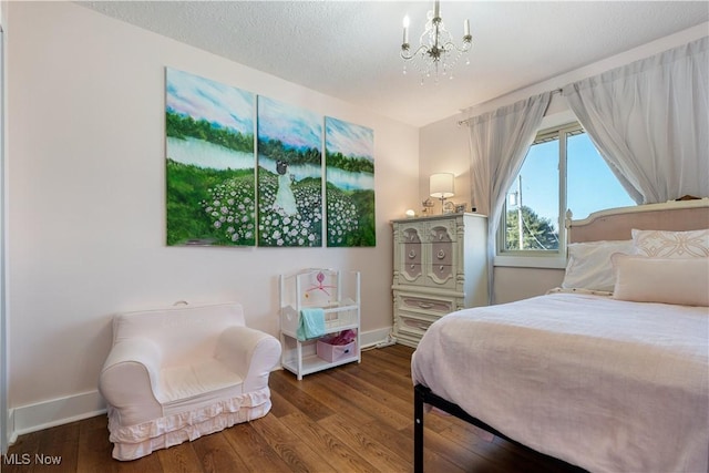 bedroom with a chandelier, a textured ceiling, baseboards, and wood finished floors