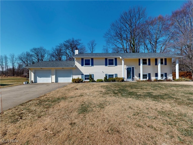 split foyer home featuring driveway, a front lawn, a chimney, and an attached garage