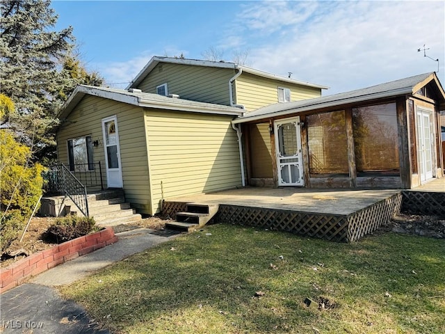 back of house featuring a lawn and a wooden deck