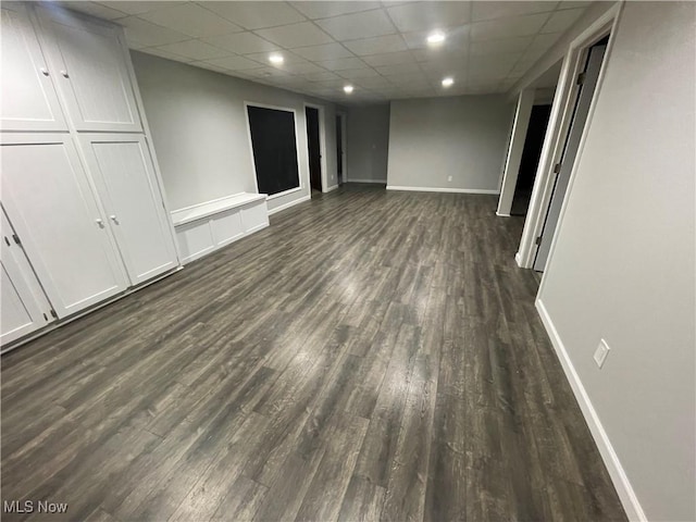 interior space with recessed lighting, a drop ceiling, dark wood finished floors, and baseboards