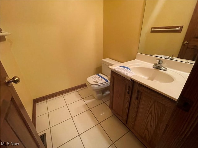 half bath featuring baseboards, vanity, toilet, and tile patterned floors