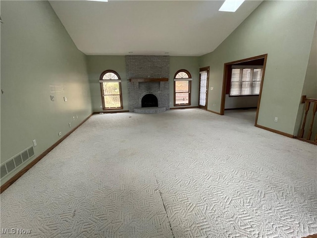 unfurnished living room featuring high vaulted ceiling, a brick fireplace, a healthy amount of sunlight, and visible vents