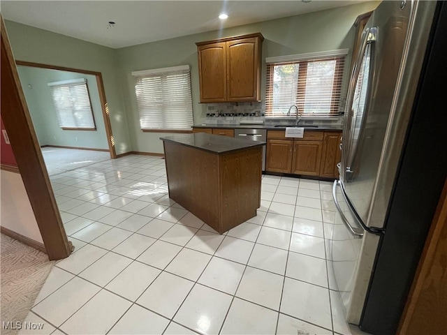 kitchen featuring dark countertops, light tile patterned flooring, a sink, and freestanding refrigerator