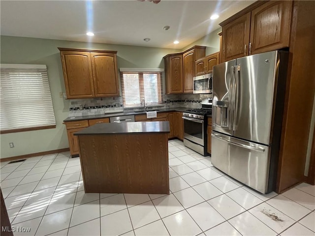 kitchen featuring appliances with stainless steel finishes, dark countertops, a kitchen island, and decorative backsplash