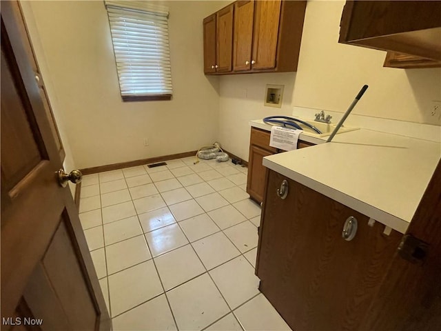 laundry area featuring cabinet space, hookup for a washing machine, baseboards, and light tile patterned floors