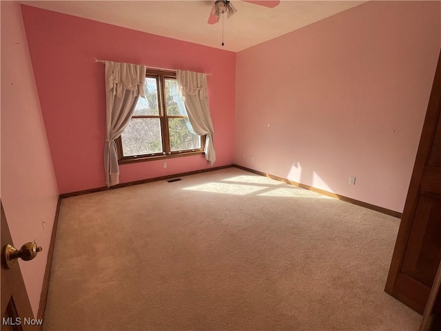 carpeted empty room with visible vents, ceiling fan, and baseboards