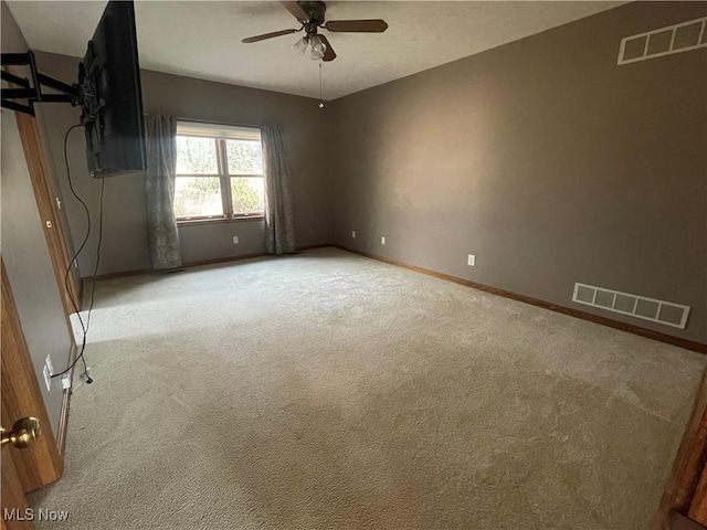 spare room featuring baseboards, a ceiling fan, visible vents, and light colored carpet