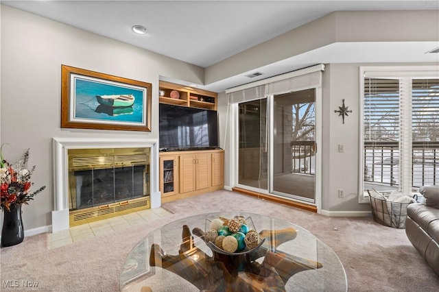 carpeted living area featuring a fireplace with flush hearth, baseboards, and built in features