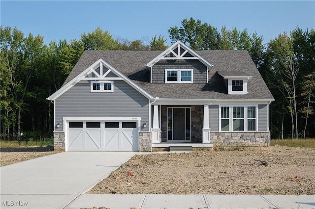 craftsman inspired home featuring stone siding, roof with shingles, an attached garage, and driveway