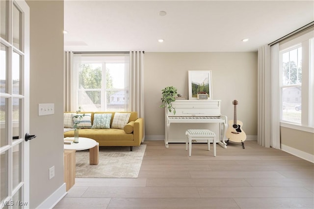 sitting room with baseboards, light wood-style floors, recessed lighting, and a healthy amount of sunlight