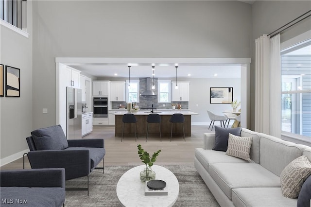 living area featuring light wood-style flooring, baseboards, and recessed lighting