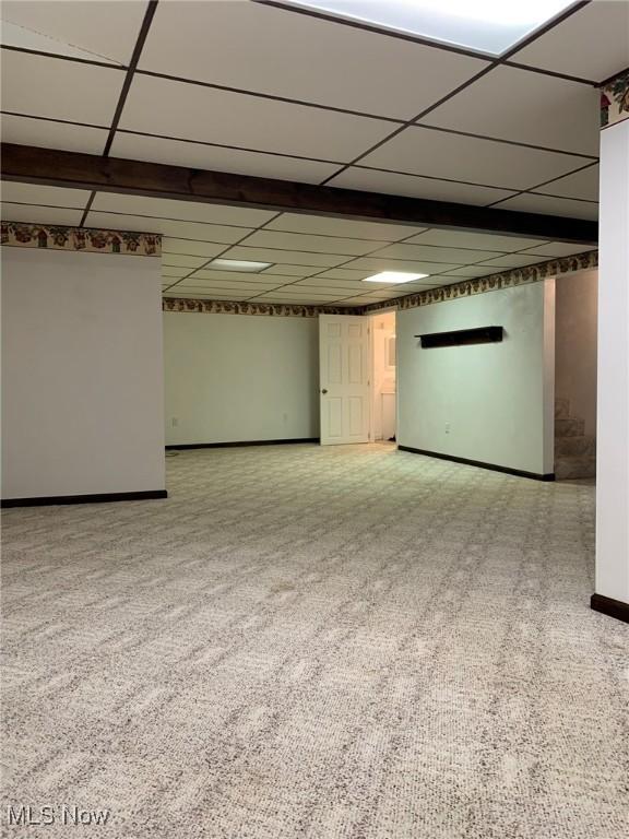 finished basement with baseboards, a drop ceiling, and carpet flooring