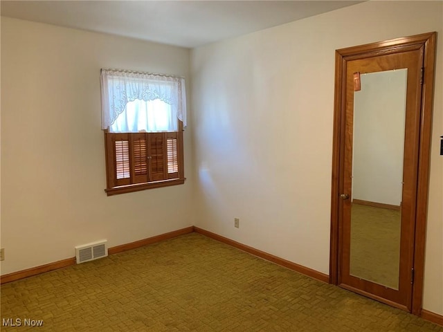 unfurnished room featuring baseboards and visible vents