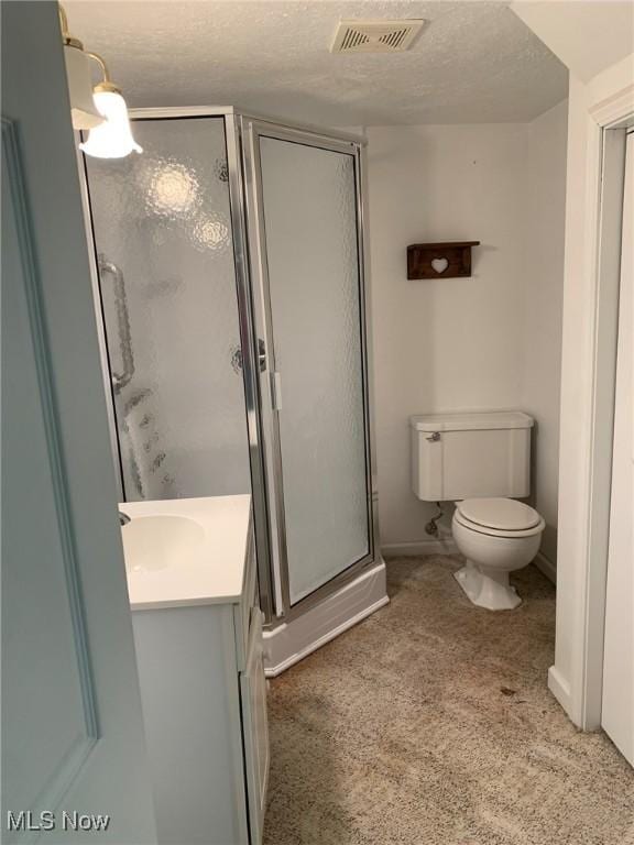 full bathroom featuring a stall shower, visible vents, toilet, a textured ceiling, and vanity