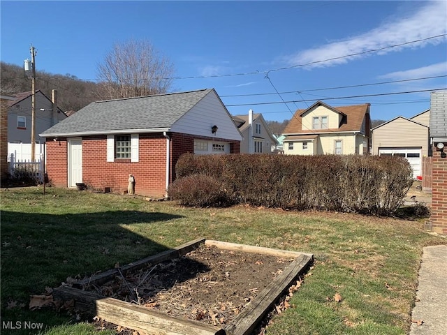 view of yard with fence, a vegetable garden, and an outbuilding