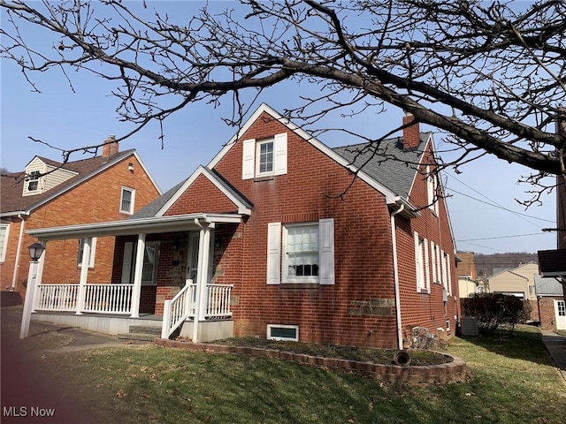 view of front of house featuring covered porch, brick siding, central AC unit, and a front yard