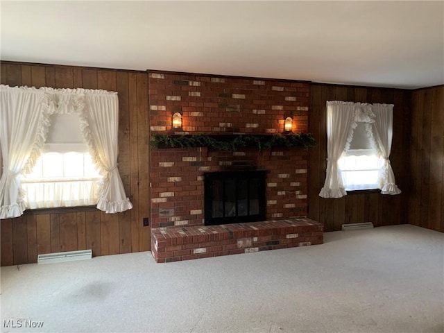 unfurnished living room with visible vents, carpet flooring, a fireplace, and wood walls