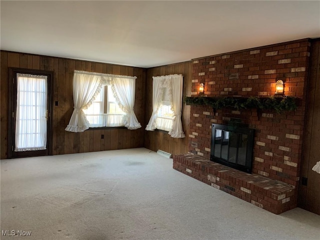 unfurnished living room featuring carpet, wood walls, and a fireplace