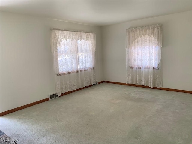 carpeted empty room featuring baseboards and visible vents