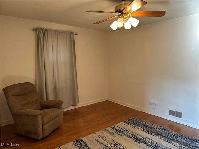 sitting room with a ceiling fan, baseboards, visible vents, and wood finished floors