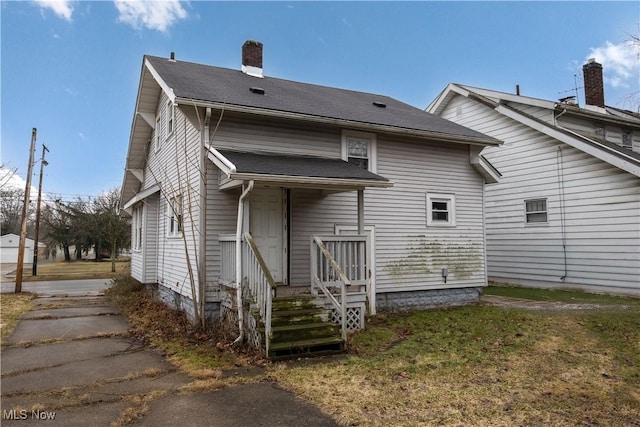 back of house with a yard and a chimney