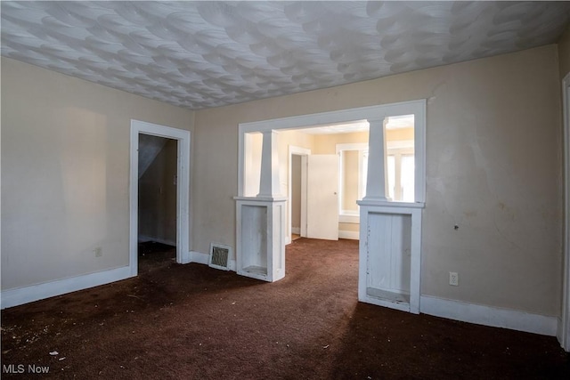 carpeted spare room featuring visible vents, decorative columns, and baseboards