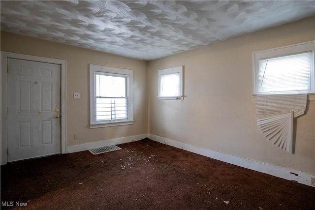 entryway with carpet flooring, visible vents, baseboards, and a textured ceiling