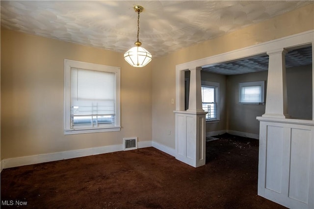 unfurnished dining area with baseboards, visible vents, and ornate columns