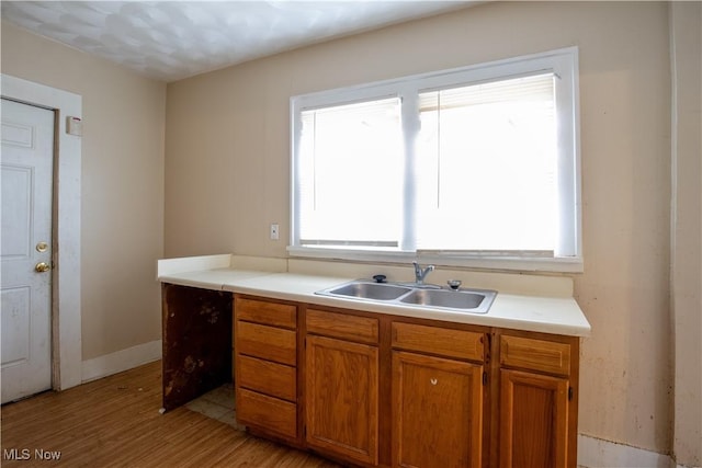 kitchen featuring light wood-style floors, a sink, a wealth of natural light, and brown cabinets