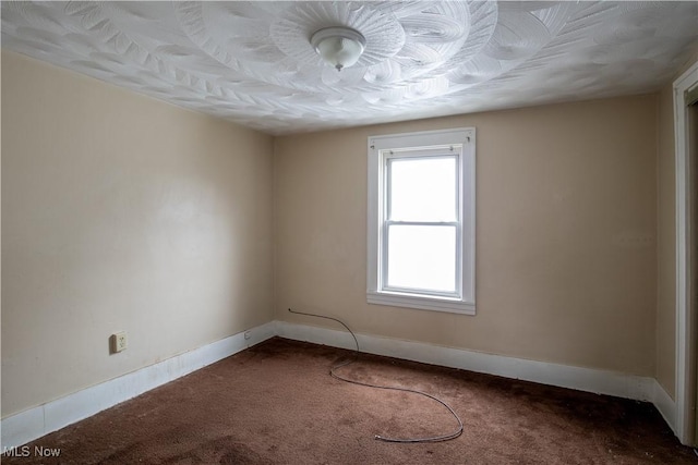 empty room with baseboards and dark carpet