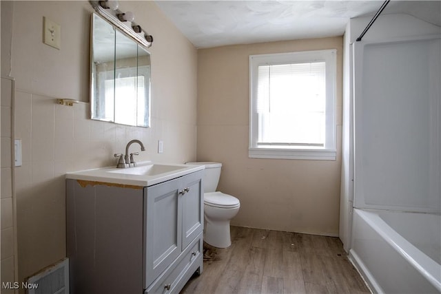 full bathroom featuring visible vents, toilet, wood finished floors, vanity, and tile walls