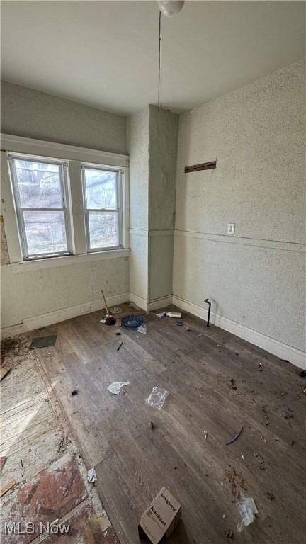 unfurnished dining area with baseboards and wood finished floors