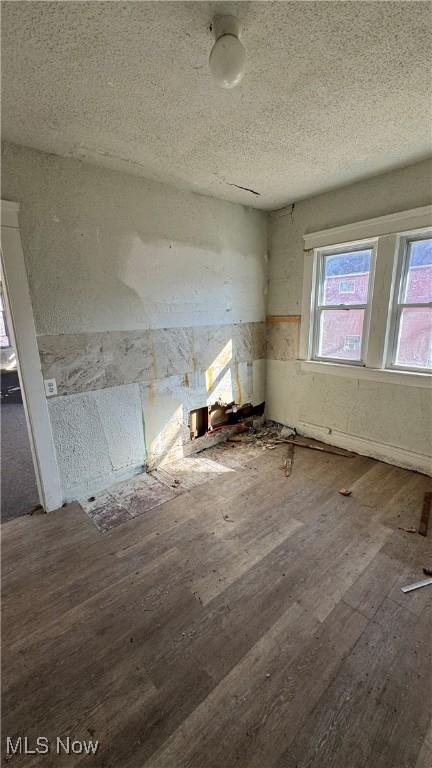 spare room with a textured ceiling and wood-type flooring