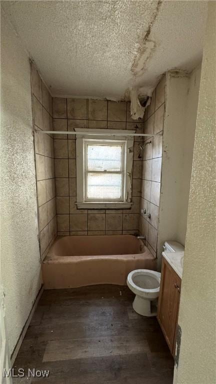 full bathroom with bathing tub / shower combination, toilet, a textured wall, wood finished floors, and a textured ceiling