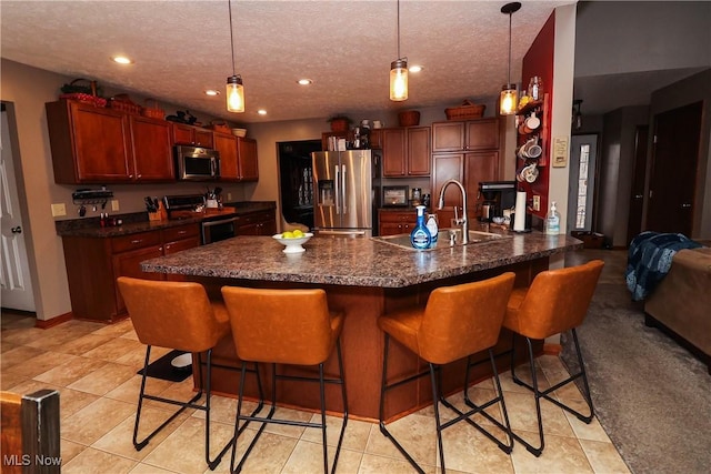 kitchen with stainless steel appliances, dark countertops, a textured ceiling, and a breakfast bar