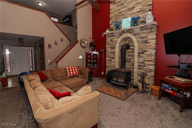 carpeted living area with a high ceiling and a wood stove