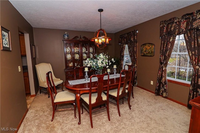 dining space featuring a textured ceiling, carpet, baseboards, and a notable chandelier