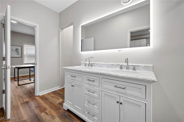 full bath featuring double vanity, baseboards, a sink, and wood finished floors