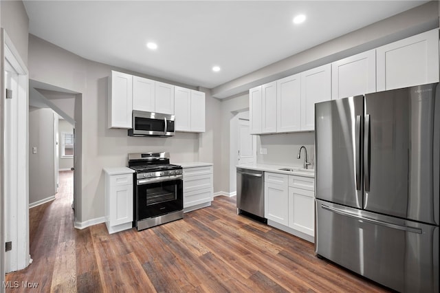 kitchen with stainless steel appliances, dark wood finished floors, light countertops, and a sink