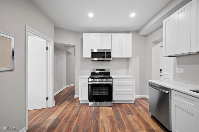 kitchen with white cabinets, baseboards, stainless steel appliances, and dark wood-type flooring